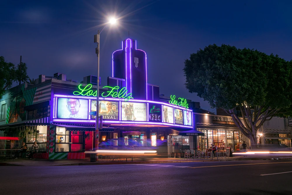 The Los Feliz Theater illuminated by neon lights at dusk, showcasing its retro design and marquee against a twilight sky in Los Angeles.