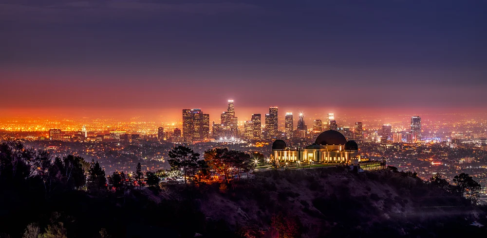 Night view of Los Angeles from Griffith Observatory, showcasing the illuminated skyline and the observatory on the hillside.