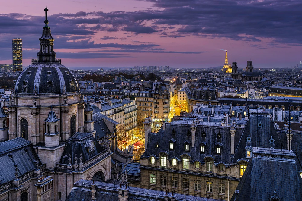 Twilight view from the Sorbonne Observatory showcasing the Paris skyline with the Eiffel Tower in the distance, illuminated by city lights.