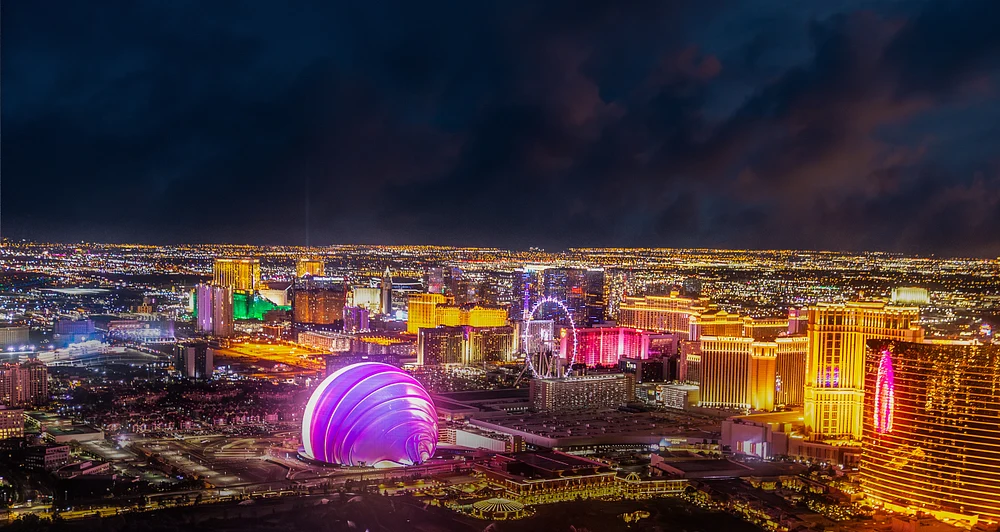 Aerial view of the Las Vegas Strip at night, showcasing vibrant lights and iconic landmarks against a dark sky.