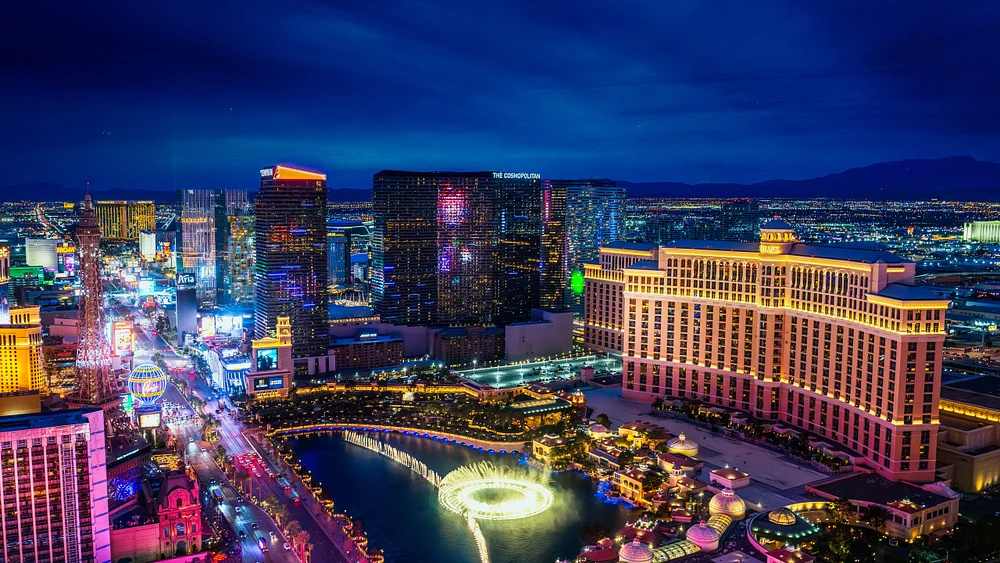 Aerial view of the Las Vegas Strip at night, featuring the Bellagio Hotel and its fountains, illuminated city skyline, and vibrant lights.