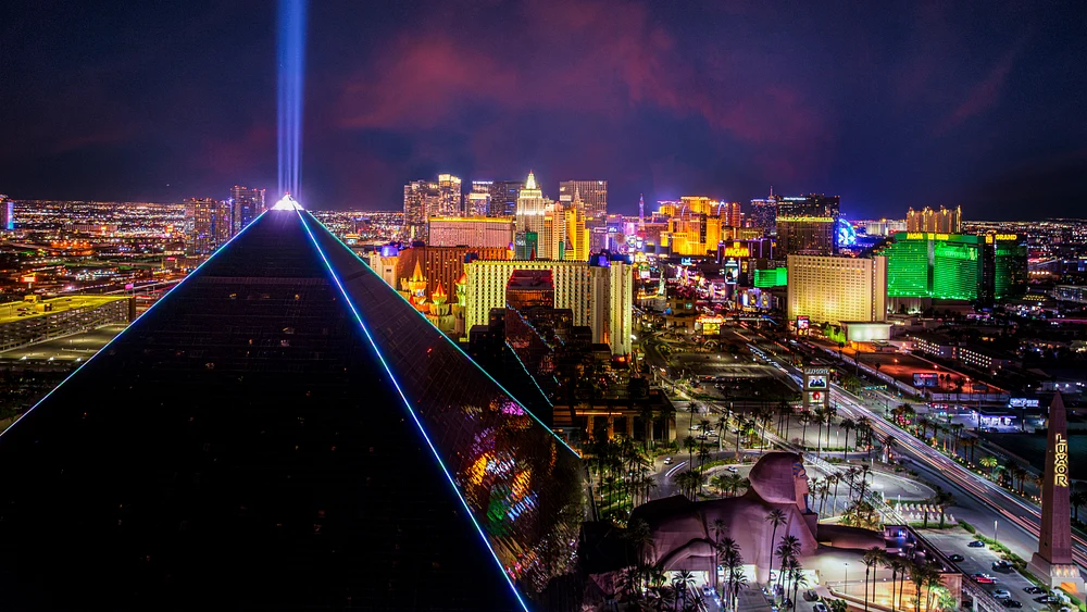 Aerial view of Las Vegas at night featuring the Luxor Hotel pyramid and the vibrant lights of the Strip.