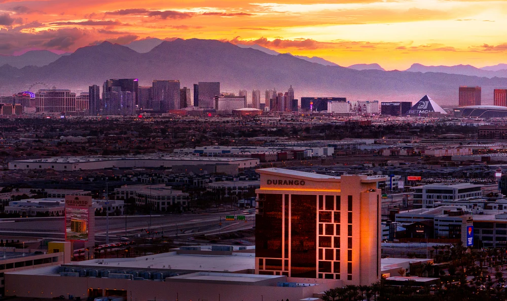 A stunning sunset over the Las Vegas skyline, featuring the Durango hotel in the foreground and mountains in the background.