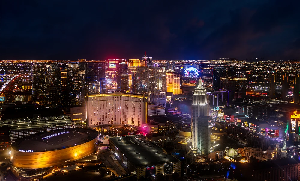 Aerial view of the Las Vegas Strip at night, showcasing illuminated hotels and casinos against a dark sky.