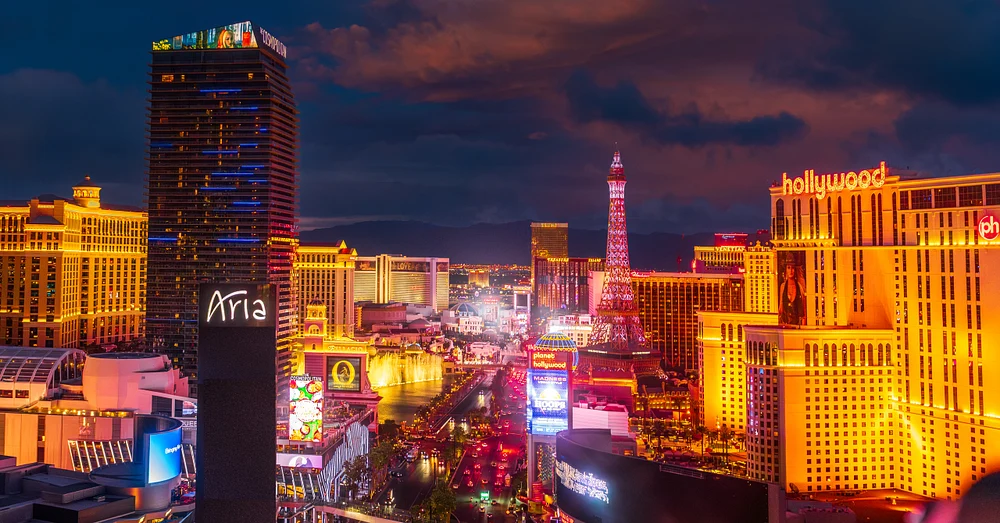 Night view of the Las Vegas Strip showcasing vibrant lights and iconic landmarks like the Aria Resort and Eiffel Tower replica.