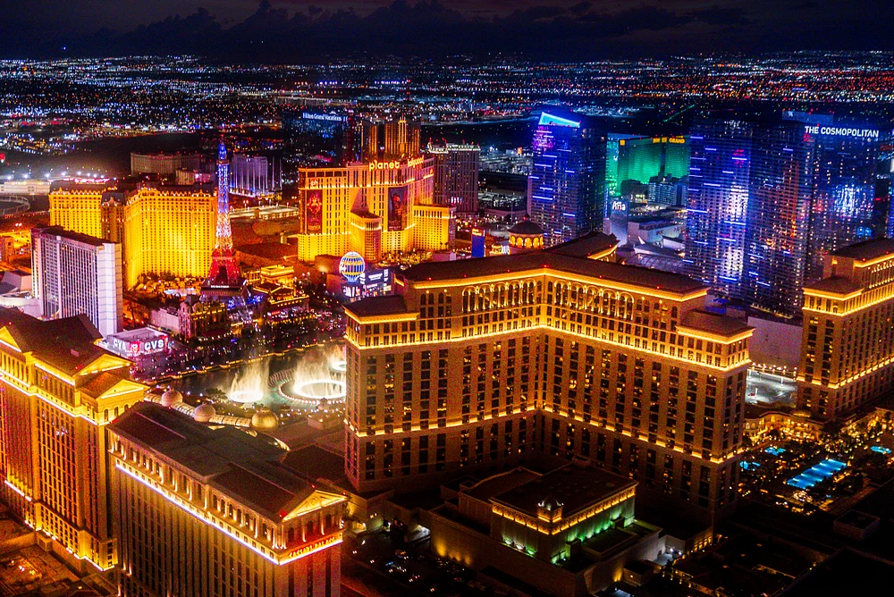 Aerial view of the Las Vegas Strip at night, showcasing illuminated hotels and casinos with vibrant lights.