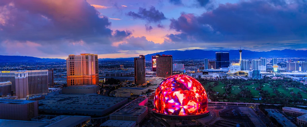 A stunning sunset view of Las Vegas featuring a colorful illuminated sphere display and the city skyline in the background.