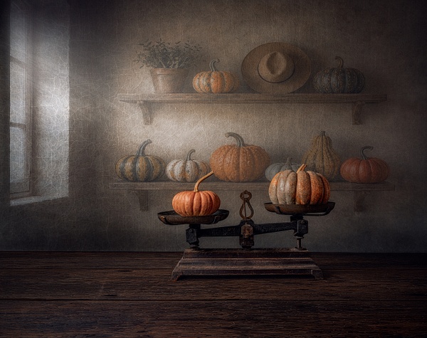 The Balance of Seasons by Marko Klavs, a fine art still life photograph of two pumpkins arranged on an antique balance scale among aged wooden shelves in a timeless interior, illuminated by soft window light.
