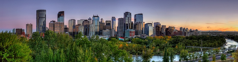 Panoramic view of Downtown Calgary - Summer with blue skies and orange horizon.