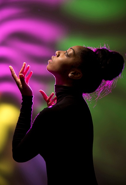 Black model appearing to pray in front of  multi color projected backdrop by  Rick Friedman - Models - Rick Friedman Photography