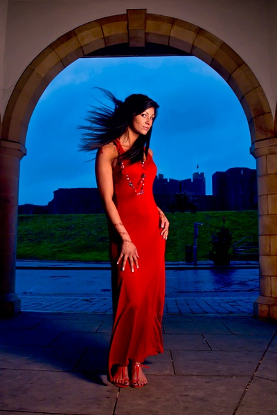 Tall brunette model in slinky red dress with castle in background in Caerphilly, Wales, UK by Rick Friedman - Rick Friedman Photography 