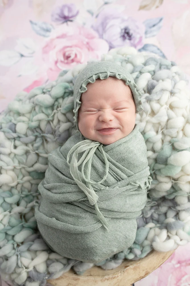 Adorable Baby Photography: Smiling Newborn in Soft Green Wrap
