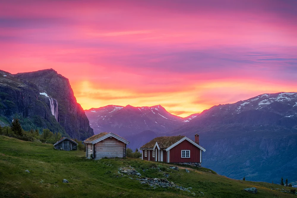 Scenic view of Torsetstolen at sunset, featuring traditional cabins and vibrant sky colors over Norwegian mountains.