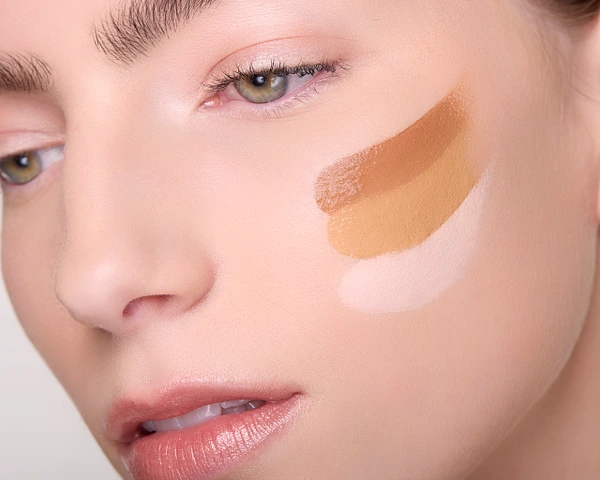 Close-up of a model's face with foundation swatches showcasing different skin tones.