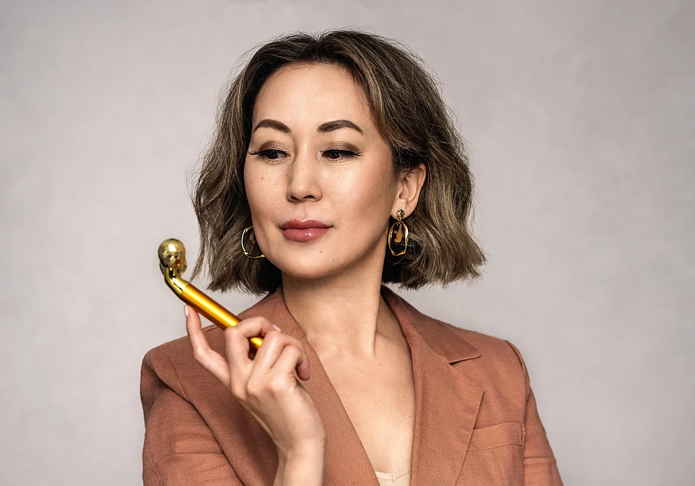 Woman Using a Golden Facial Roller for Skincare