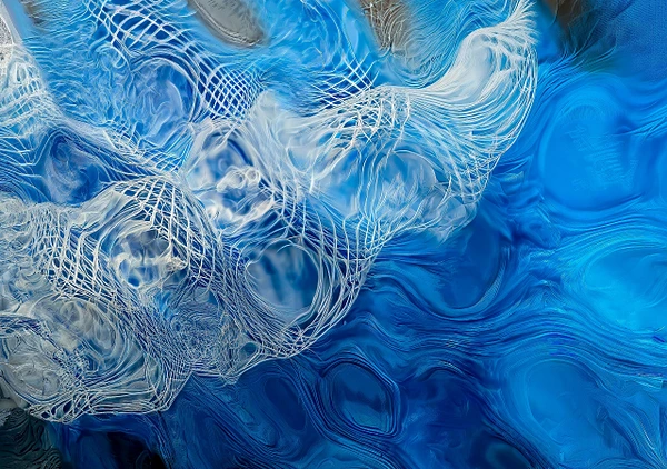 Intricate pale filaments swirl across deep cobalt currents, resembling delicate marine lace suspended in moving water