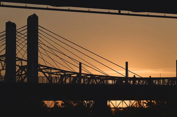 Silhouette of a bridge against a vibrant sunset sky.