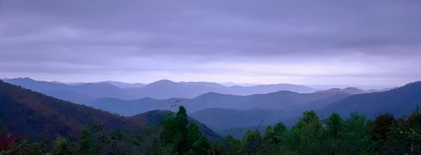 A panoramic view of a mountain range at twilight with soft hues.
