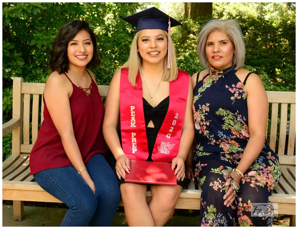 Celebratory Graduation Moment with Family A proud graduate in cap and gown poses with family members outdoors.