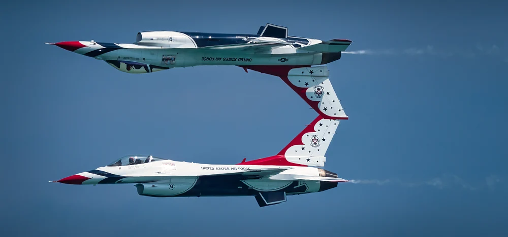 U.S. Air Force Thunderbirds performing a synchronized aerial maneuver against a clear blue sky.