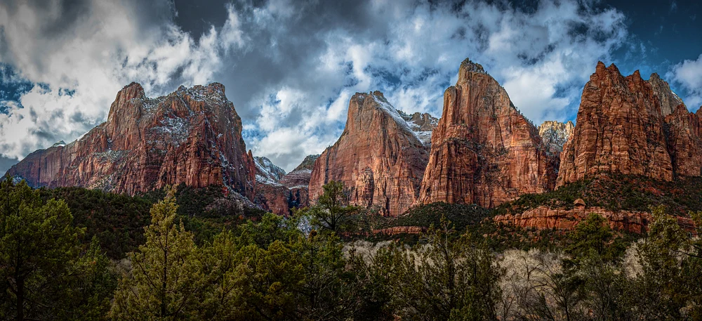 Panoramic view of the Court of the Patriarchs showcasing towering red rock cliffs under a dramatic sky.