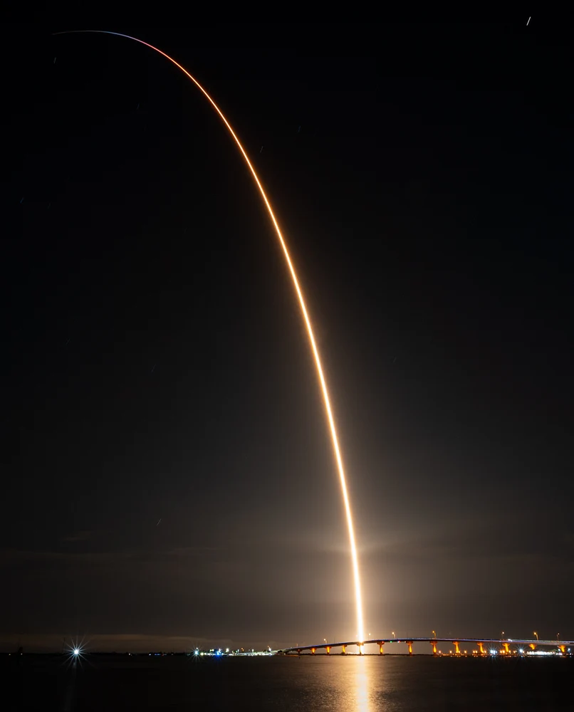 FalconX-6 rocket launch captured at night with bright light trails against dark sky.