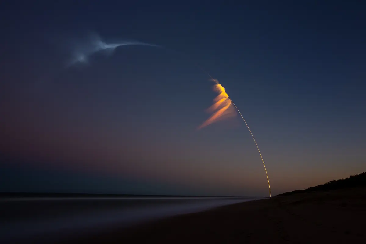 Falcon Heavy rocket launch captured at dusk with vibrant trails in the sky.