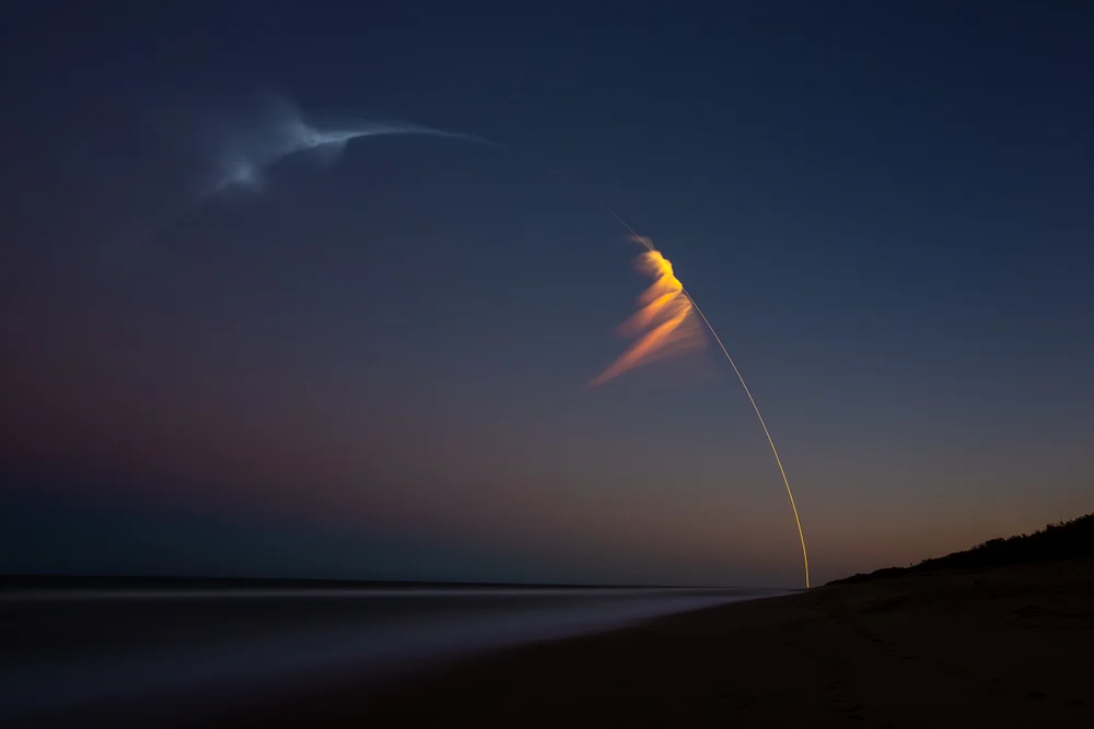 Falcon Heavy rocket launch captured at dusk with vibrant trails in the sky.