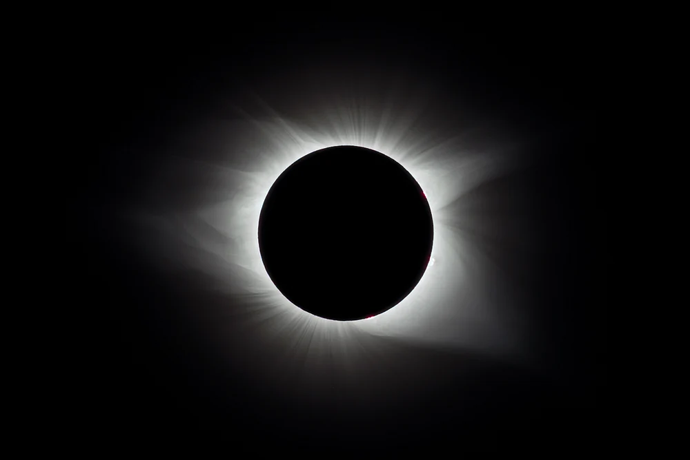 A total solar eclipse showing a darkened sun surrounded by glowing corona.