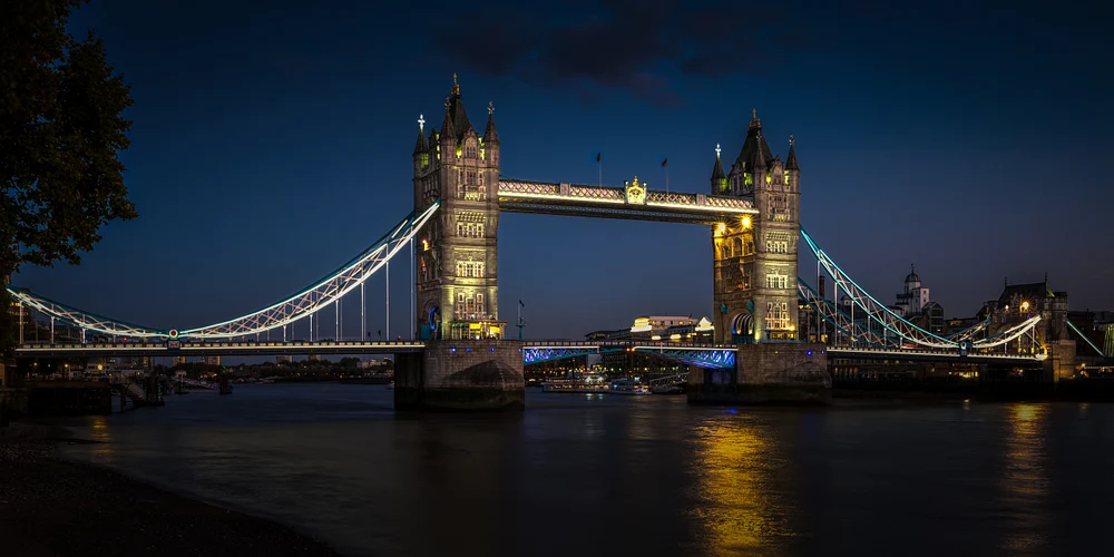 Tower Bridge illuminated at dusk with reflections on the river.