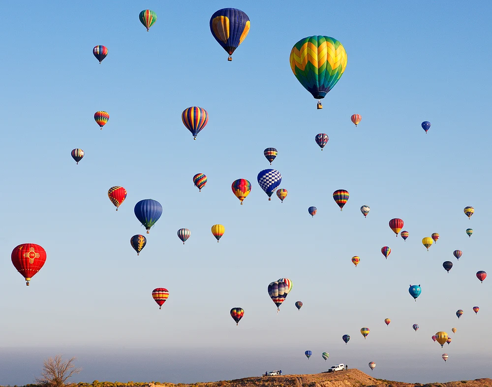 A vibrant display of colorful hot air balloons soaring in the clear sky at Albuquerque Balloon Fest.
