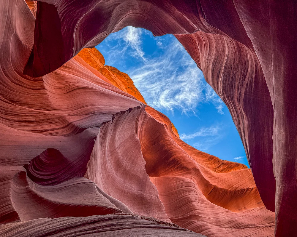 View from inside Lower Antelope Canyon showcasing colorful sandstone walls and blue sky.