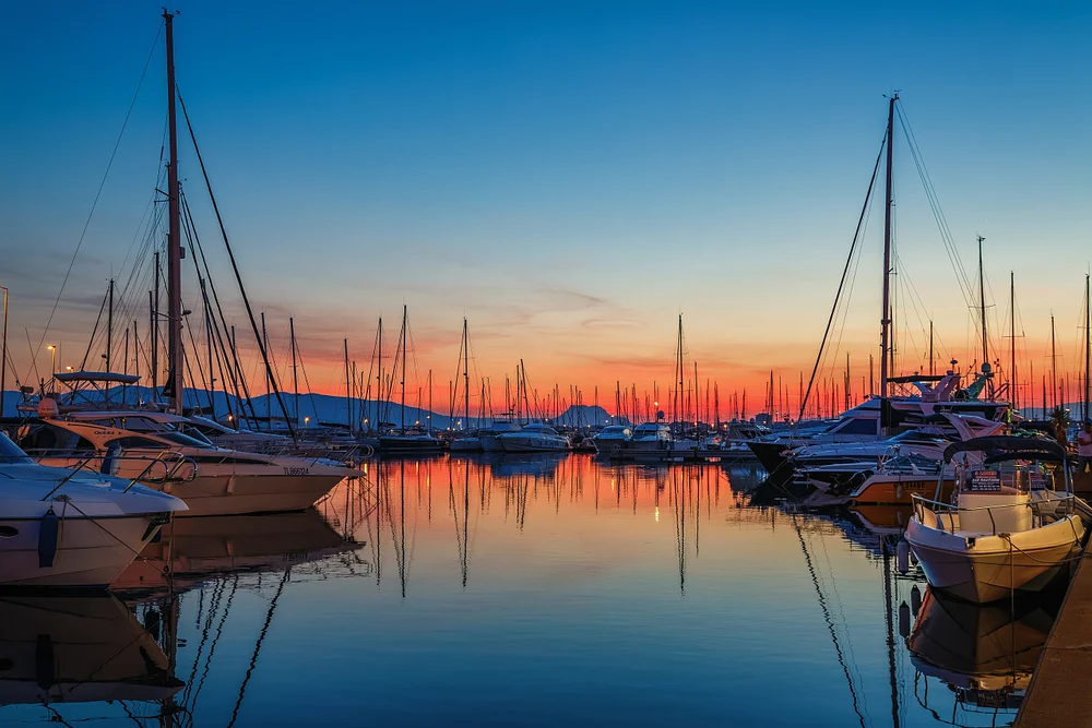 Sunset illuminates Saint-Rapha&euml;l&rsquo;s Vieux-Port, with sailboats, yachts, mast silhouettes, and calm mirrored water