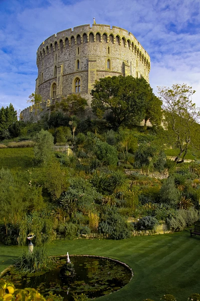 Windsor Castle surrounded by beautiful gardens and a reflective pond.