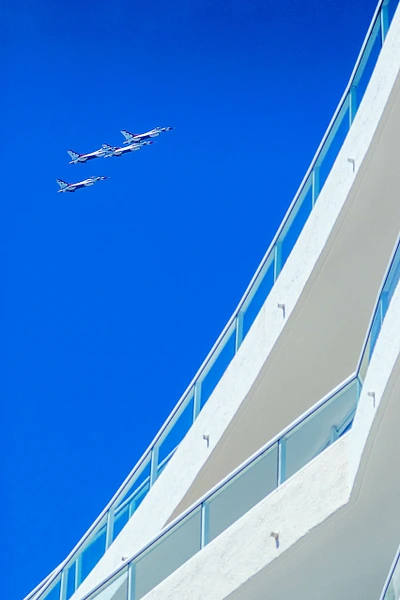 USAF Thunderbirds performing over the Ritz-Carlton hotel in Fort Lauderdale against a clear blue sky.