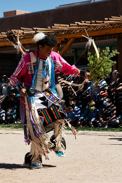 Native American dancer in colorful regalia performing a traditional dance outdoors.