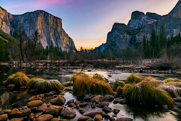 Sunset over Yosemite Valley with granite cliffs and reflective river.