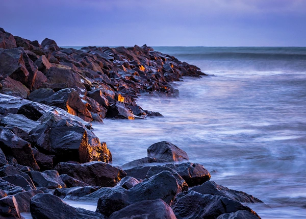 Coastal landscape of Vik, Iceland at dusk with volcanic rocks and gentle waves.