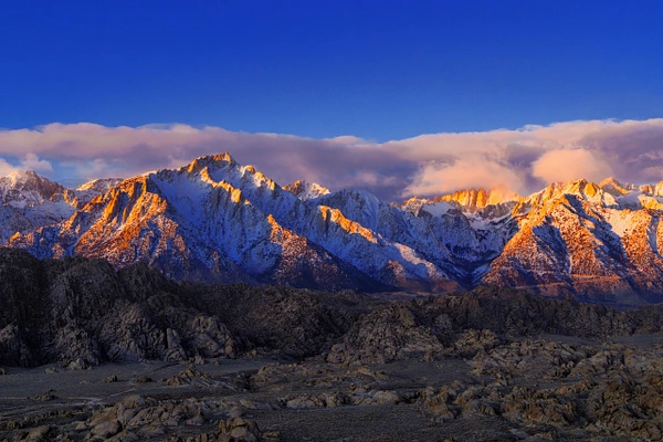 Sierra Nevada Mountains illuminated by sunset, showcasing rugged peaks and rocky terrain.